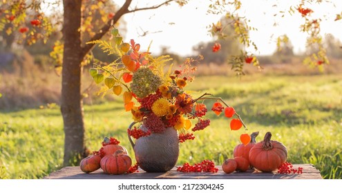 bouquet autumn flowers in rustic jug on wooden table outdoor at sunset - Shutterstock ID 2172304245