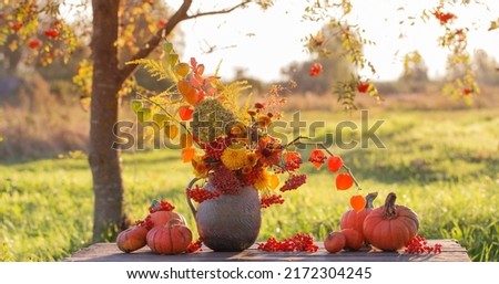bouquet autumn flowers in rustic jug on wooden table outdoor at sunset