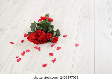 Bouquet of beautiful red roses and petals on wooden floor. Valentine's Day celebration - Powered by Shutterstock