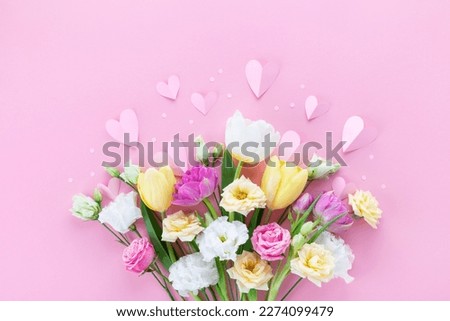 Bouquet of beautiful spring flowers and paper hearts on pastel pink table for Happy mothers day. Flat lay.