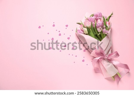 Bouquet of beautiful tulip flowers and paper hearts on pink background, top view