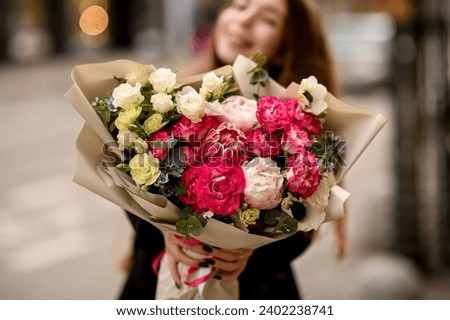 Bouquet of beautiful white and pink flowers in the foreground, a brunette woman in the background, blurred background