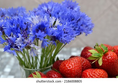 Bouquet of blue cornflowers and ripe red strawberries