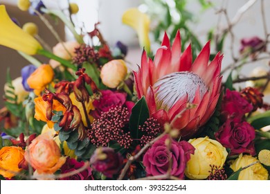 Bouquet. Bright bouquet. Artwork. Bright bouquet of red, yellow, pink, purple flowers and greenery is on the table, against a white wall - Powered by Shutterstock