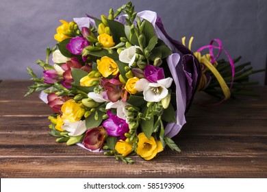 Bouquet of colorful fresh freesia on a wooden background - Shutterstock ID 585193906