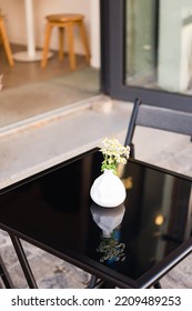 Bouquet Of Daisies In A White Vase On The Black Glass Table Cafe Outside	