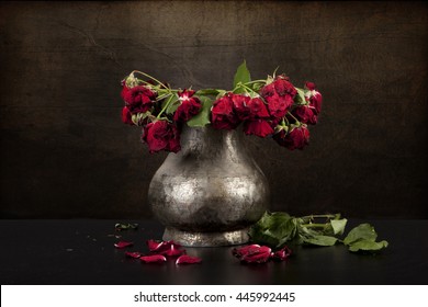 bouquet of dead red roses in pewter vase with grunge background