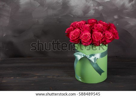 Bouquet of delicate red roses in green gift box on dark grey rustic wooden background. Home decor. card for copy space