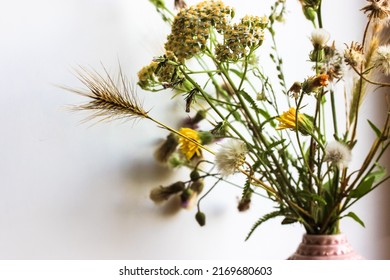 Bouquet of different wildflowers in a pink vase close-up against white wall at summer day. Different flowers in home interior. Cosy homy atmosphere. Natural background. Happy mothers day, women's day.