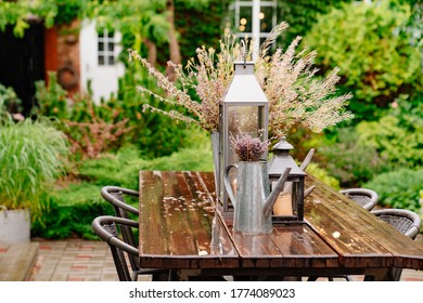 bouquet of dried flowers and candles on the table for dinner outside in the yard in the rain in the summer.