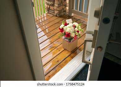 A Bouquet Of Flowers In A Carton Box On A Porch Of A House Through Open Door. Surprise Contactless Delivery Of Flowers For Woman. Delivery Of Goods Home During Quarantine. A Pleasant Unexpected Gift.