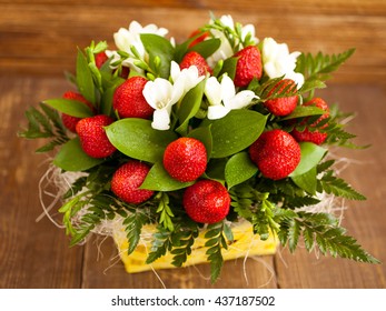 Bouquet from flowers and fruit. Ripe strawberry and white freesia.