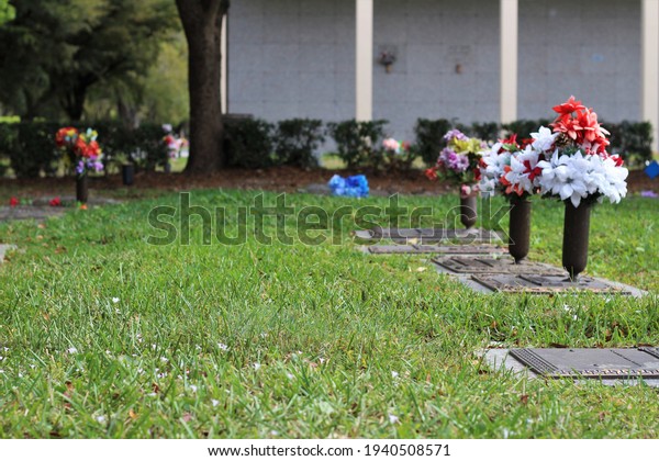 Bouquet of flowers laying on top of a cemetery plaque of\
a beloved lost one. Graveyard site, loss of a loved one concept.\
