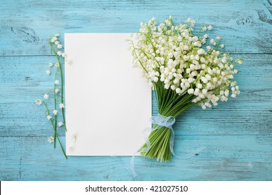 Bouquet Of Flowers Lily Of The Valley And Empty Paper Sheet On Turquoise Rustic Table From Above, Beautiful Vintage Card, Top View, Space For Text, Flat Lay.