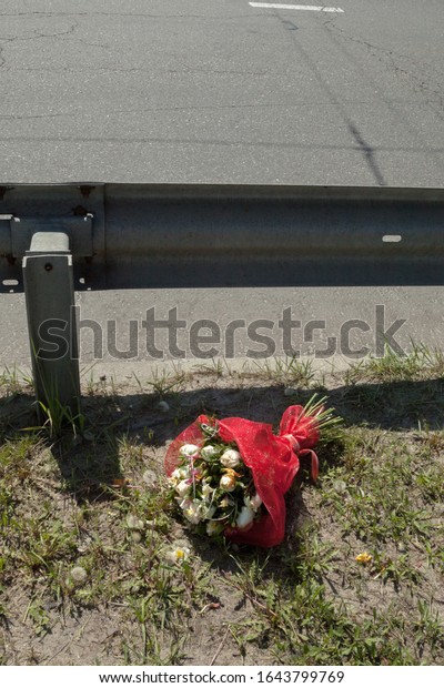 Bouquet of flowers near the road. Flowers near the\
metal road fence.