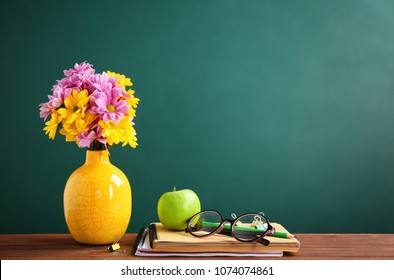 Bouquet of flowers and notebooks with eyeglasses on table. Teacher day celebration