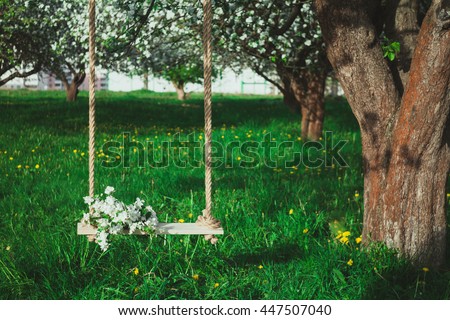 Bouquet of flowers on the tree swing in the blossoming apple orchard