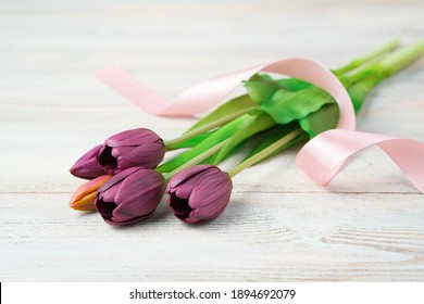 A Bouquet Of Flowers With A Ribbon Lies On A Light Wooden Table. Side View, With Space To Copy. Concept Of Festive Backgrounds, March 8, Spring.