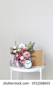 A Bouquet Of Flowers For A Woman On The Bedside Table On The Day Of The Holiday On March 8, St. Valentine's Day, Mother's Day, Wedding Day, Birthday. Flower Arrangement, Photo Frame, Alarm Clock.