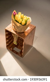 Bouquet Of Flowers Wrapped In Paper And Placed On A Small Crate In A Studio