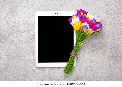 Bouquet of freesia flowers and white tablet with black screen on grey background Floral holiday card Top view Flat lay Happy Mother's, Valentine's, Women's Day, Flower shop concept Mock up - Powered by Shutterstock