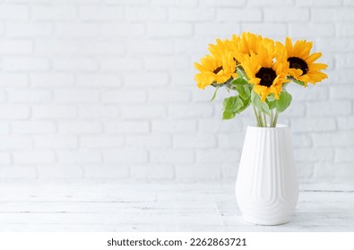 A bouquet of fresh sunflowers in a vase against the background of a white brick wall. copy space for text. Spring or autumn concept, yellow color - Powered by Shutterstock