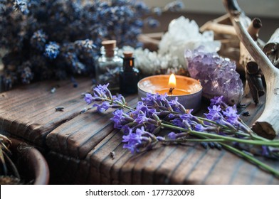 Bouquet of lavender, driftwoods, lighted candle and tiny glass bottles on a wooden background. Alternative medicine, aromatherapy, Wicca, Boho or esoteric background.