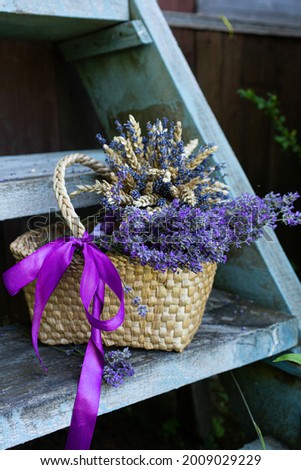 Bouquet of lavender flowers in a basket with straw on a wooden ladder