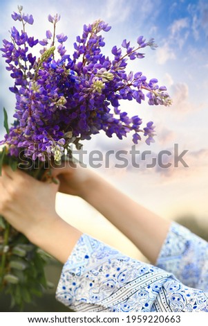 Frau blickt vom Balkon herab in den sonnigen, warmen Morgen.