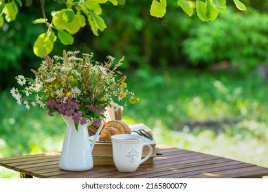 Bouquet Of Meadow Flowers, Croissant, Cup Of Tea Or Coffee, Books On Table In Summer Garden. Rest In Garden, Reading Books, Breakfast, Vacations In Nature Concept. Summertime In Garden On Backyard