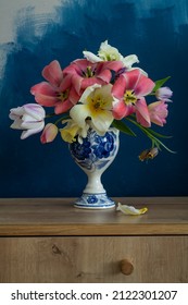 A bouquet of open tulips in a Dutch vase on navy blue background
