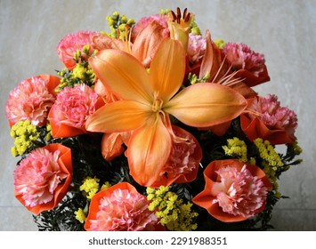 Bouquet of orange lilium flowers and bicoloured carnation flowers with yellow coloured tiny flowers. Bright orange coloured bouquet. Fresh and healthy flowers. Present gift celebration. - Shutterstock ID 2291988351