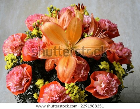 Bouquet of orange lilium flowers and bicoloured carnation flowers with yellow coloured tiny flowers. Bright orange coloured bouquet. Fresh and healthy flowers. Present gift celebration.