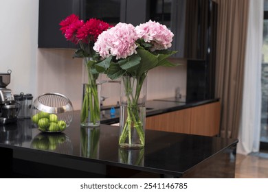  A bouquet of pink Dutch hydrangeas and a bouquet of red dahlias, along with an iron vase filled with green apples on a kitchen table in a modern kitchen. - Powered by Shutterstock