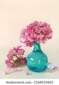 Bouquet Of Pink Hydrangea Flowers In Blue Glass Vase On Light Background. Pink Hortensia Bunch With Pink Petals As Home Decoration. Minimalist Pink Aesthetic Concept. Pastel Peach Background.