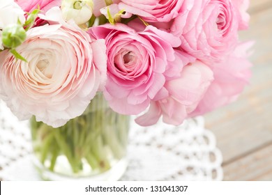 Bouquet of pink ranunculus in vase on wooden background