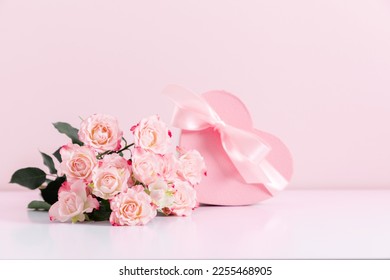 Bouquet of pink rose flowers and heart shaped gift box with satin bow on pastel pink table background. Birthday, Wedding, Mother's Day, Valentine's day, Women's Day. Front view - Powered by Shutterstock