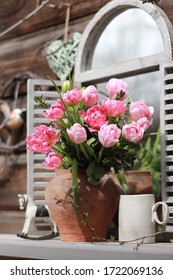 A bouquet of pink tulips in a clay vase on the window in the garden
