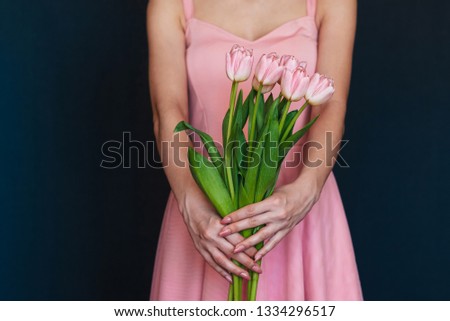 bouquet of pink tulips in the hands of a girl in a dress close-up