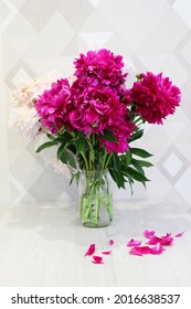 Bouquet of pink and white peonies on a wooden table, red garden peonies in a transparent glass vase jar on a white background, colorful assorted bouquet. Cozy home concept. vertical image. place for