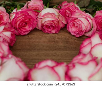 A bouquet of pink and white roses arranged in a heart shape on a wooden surface. The roses are the main focus of the image, and the heart shape adds a romantic and elegant touch to the arrangement. - Powered by Shutterstock