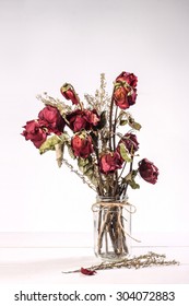  Bouquet of red dried roses in glass vase on white background