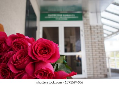 Bouquet Of Red Roses Against The Background Of The Maternity Ward Doors