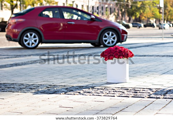 Bouquet\
of red roses in a box and red car on\
background