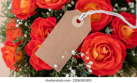 Bouquet Of Red Roses With Empty Paper Note Copy Space Decorated In Hat Box On Light Background. Tied Bow On Top. Flower Delivery Gift For Holiday. Flower Arrangement. Present Idea Greeting Card