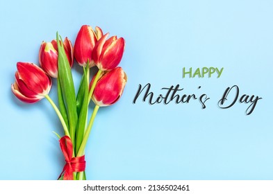Bouquet of red tulips, text Happy Mother's Day on blue background Top view Flat lay Holiday greeting card