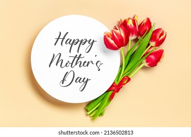 Bouquet of red tulips, text Happy Mother's Day on white podium on beige background Top view Flat lay Holiday greeting card