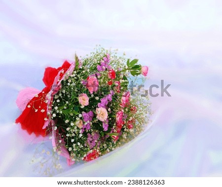 Bouquet with redroses and pink flowers on a silk background.