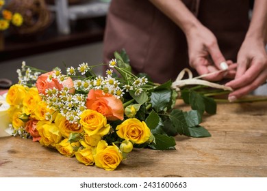 Bouquet of roses and daisies on the table the store close-up.Florist in an apron tying a ribbon on a bouquet.The process of creating a bouquet.Education and courses in floristry. - Powered by Shutterstock