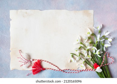 A bouquet of spring flowers of snowdrops and a red-white cord with tassels and hearts, martenitsa symbol, paper for congratulations text on a colorful background. Postcard for the holiday in March 1.